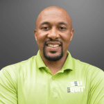 smiling man with goatee and wearing a bright green shirt standing against a gradient background